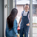 © zinkevych | freepik.com | Handwerkerbesuch Fröhlicher Mann in blauer Arbeitskleidung mit Werkzeugkoffer...