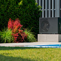 © StockSeller | freepik.com | Außeneinheit einer Wärmepumpe am Rand eines Pools Dekorativpflanzen wachsen...