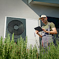 © StockSeller | freepik.com | Techniker, der an einem sonnigen Tag ein Tablet benutzt, um eine Wärmepumpe...